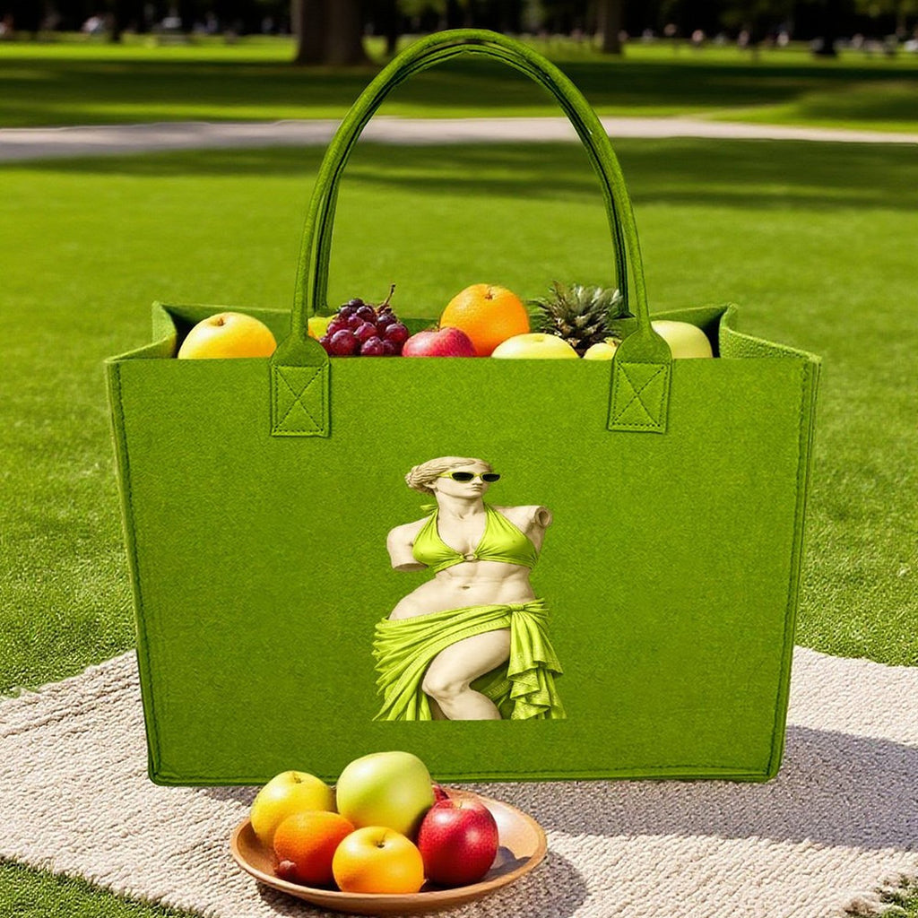 Light green felt tote bag filled with fresh fruit on grassy lawn