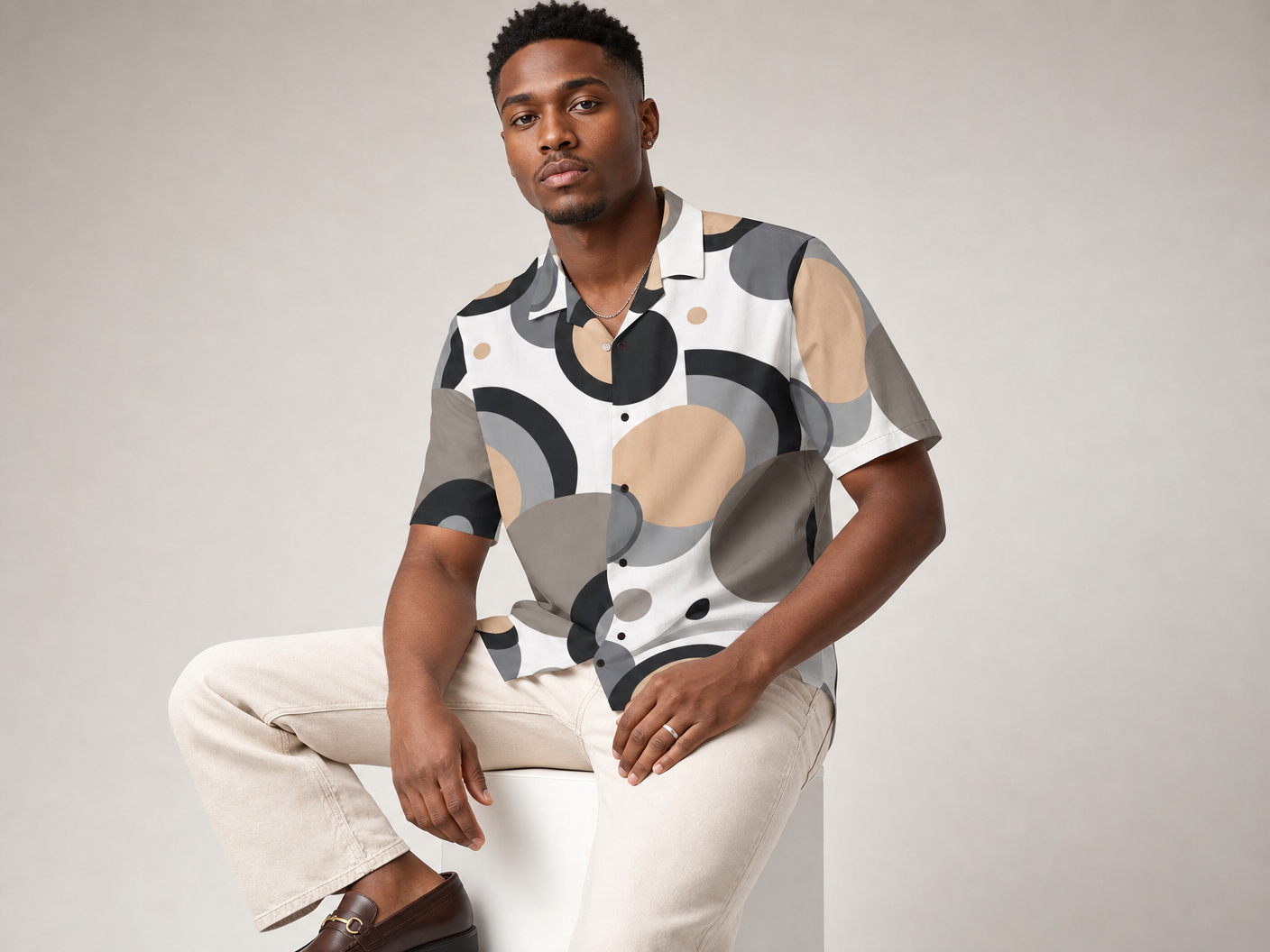 Male model wearing the Rich and Rich Men’s Beige Circular Dimension Designer Shirt with a boxy fit, short sleeves, notch lapel collar, and beige circular abstract design.