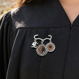 Double round photo charm brooch with Burnt Orange Roses motif and a small graduation cap charm — side view