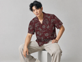 Male model wearing the Rich and Rich Men’s Burgundy Designer Fusion Shirt with a boxy fit, short sleeves, notch lapel collar, and rich burgundy fusion designer pattern.