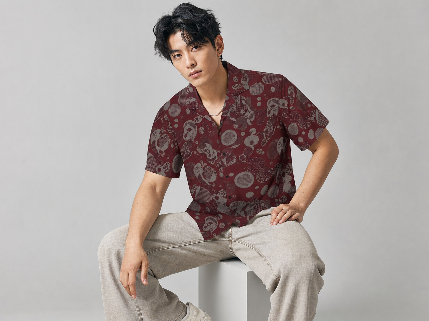 Male model wearing the Rich and Rich Men’s Burgundy Designer Fusion Shirt with a boxy fit, short sleeves, notch lapel collar, and rich burgundy fusion designer pattern.