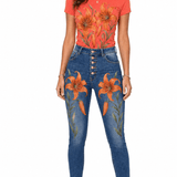 Coral tee with large orange and gold tiger lily blooms paired with high-waist denim embroidered with matching flo — rear view