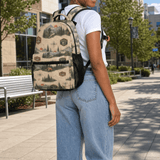 Beige 17-inch backpack with front pocket, mesh side pockets, padded straps, and orange buckle detail — side view