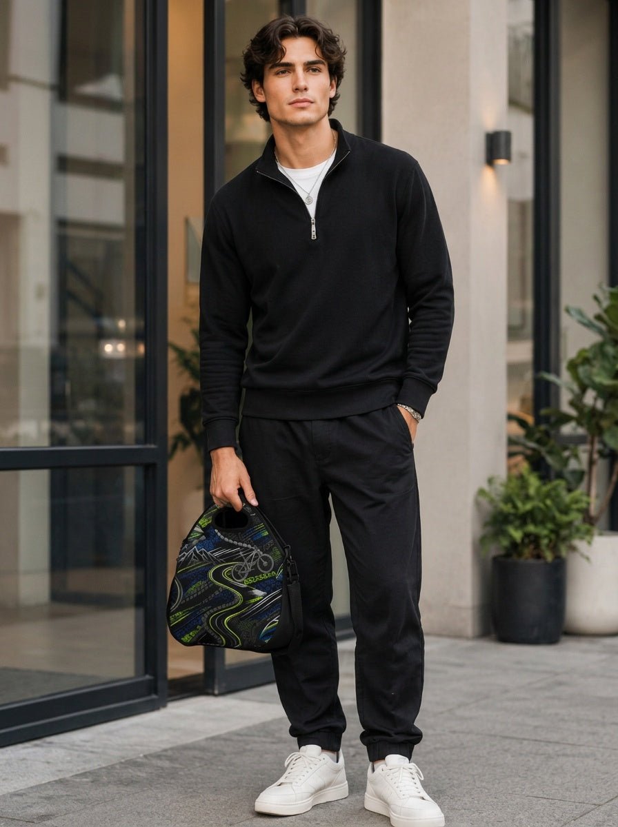 Man holding black insulated lunch tote by top handle indoors