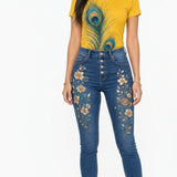 Sunflower yellow tee with peacock feather print paired with embroidered denim jeans