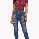 Fuchsia tee with gold and emerald twin dragon graphic paired with denim embroidered with floral and scale motifs