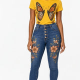 Sunflower yellow tee with monarch butterfly graphic paired with high-waist blue jeans with floral embroidery